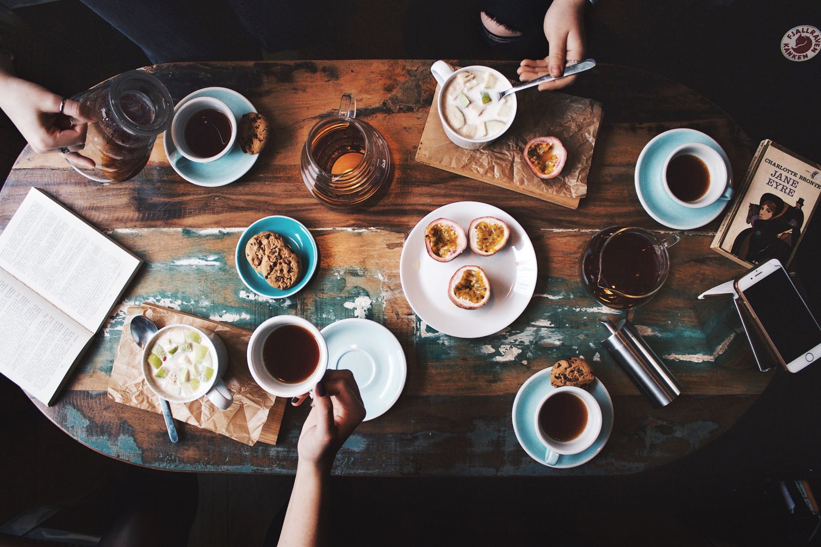 A weekend brunch table seen from above, covered with coffees, cookies and passion fruit