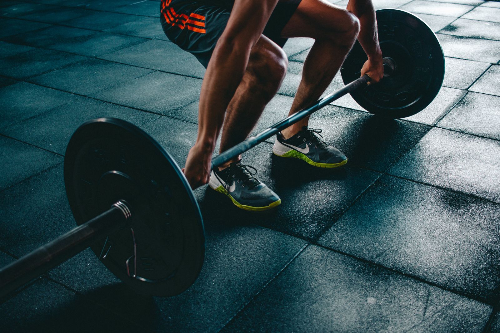 Athlete loading a barbell under hard industrial light at FORGE gym