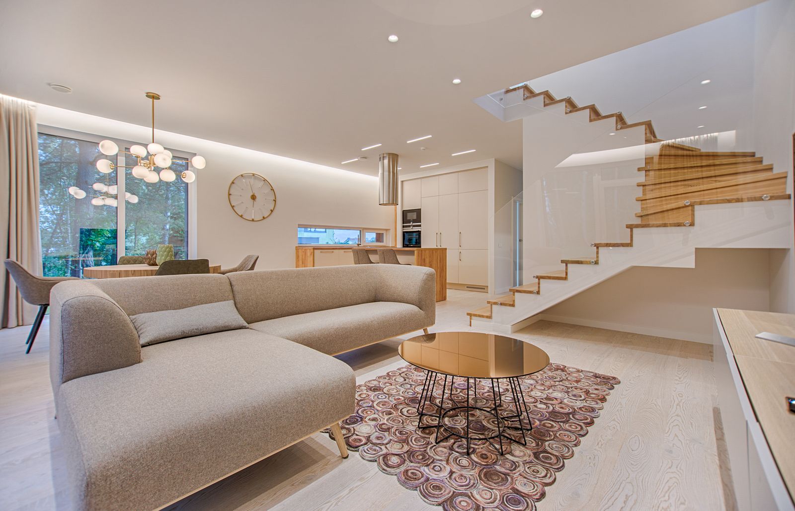 Double height living room of Villa Sera with a floating oak staircase and soft daylight