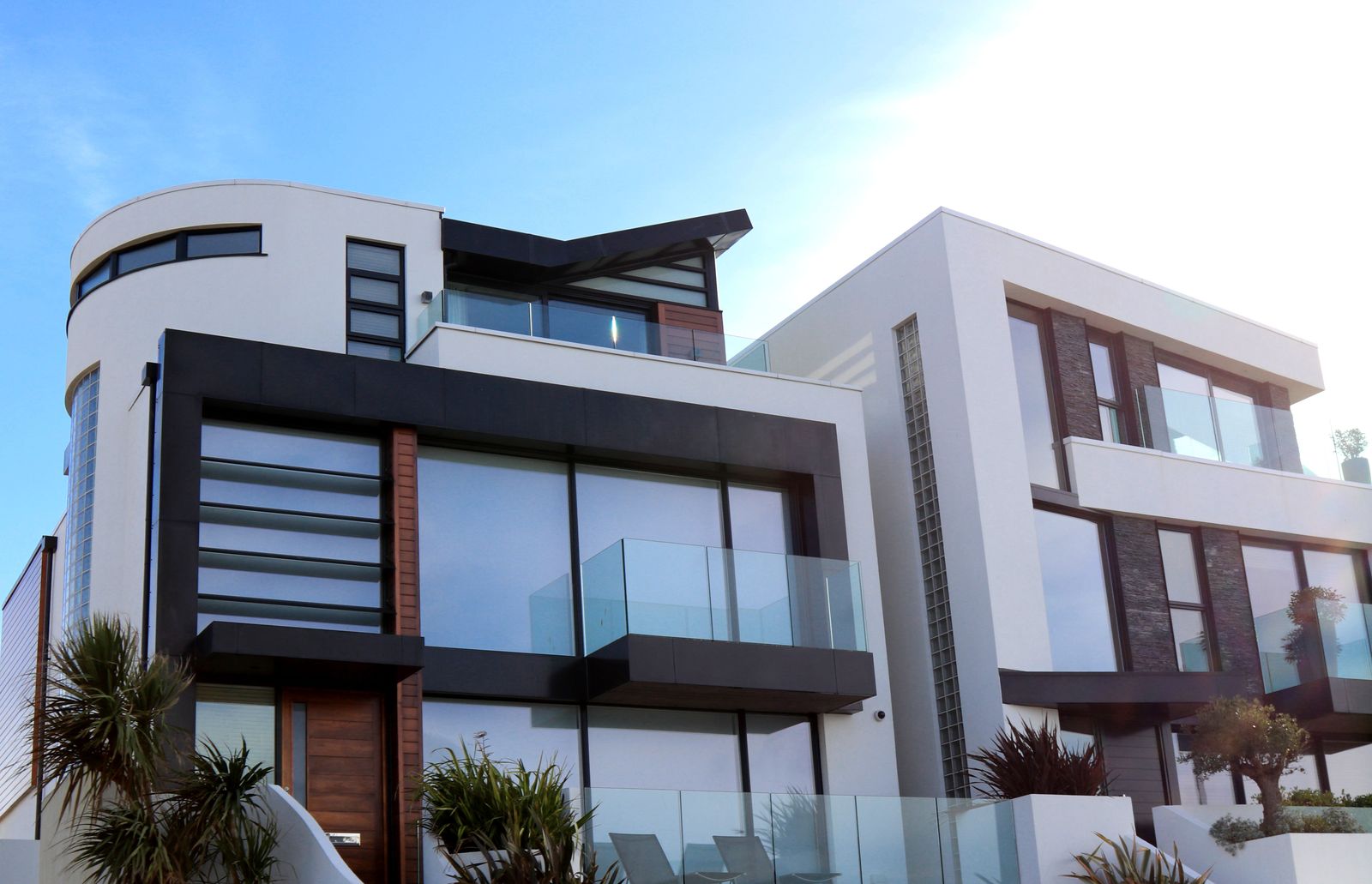 White contemporary villa exterior with glass balustrades and palm planting
