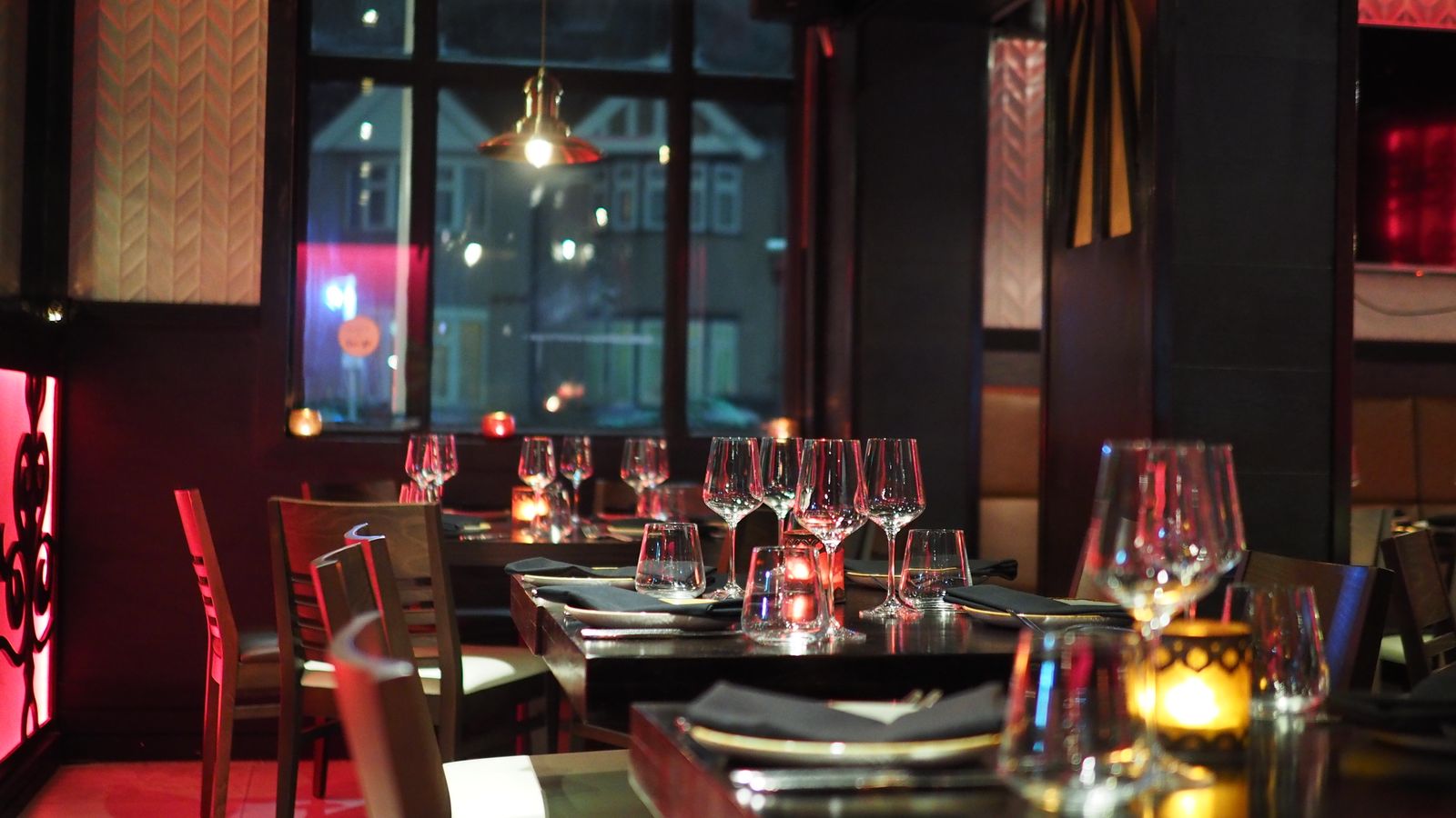 Candlelit dining room of Nara with dark timber tables and glassware